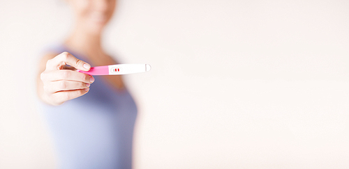 health care concept - close up of happy woman holding and showing pregnancy test