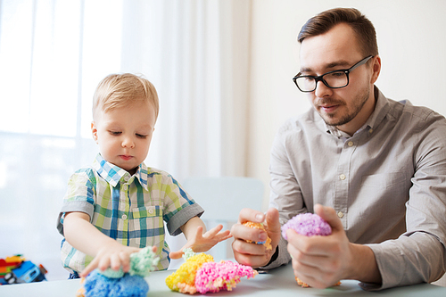 family, childhood, creativity, activity and people concept - happy father and little son playing with ball clay at home