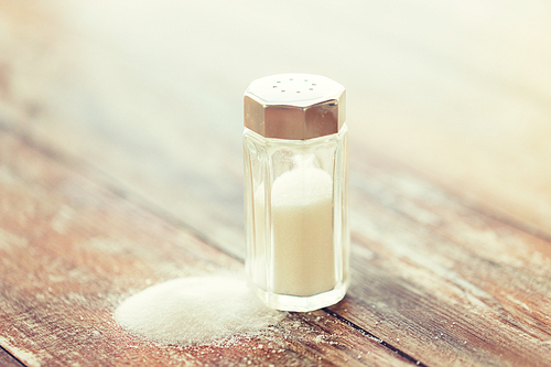 food, junk-food, cooking and unhealthy eating concept - close up of white salt cellar on wooden table