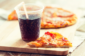 fast food, italian kitchen and eating concept - close up of pizza with cup of coca cola drink on wooden table