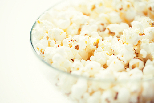 fast food, junk-food and unhealthy eating concept - close up of popcorn in glass bowl