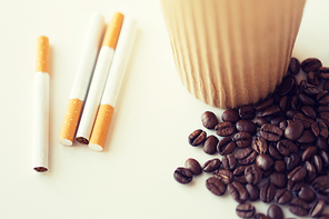 bad habits, addiction and unhealthy lifestyle concept - close up of cigarettes, coffee cup and beans on table