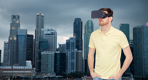 3d technology, virtual reality, travel, entertainment and people concept - young man with virtual reality headset or 3d glasses over singapore city skyscrapers background