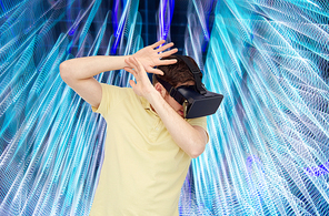 3d technology, virtual reality, entertainment and people concept - happy young man with virtual reality headset or 3d glasses playing game over spiral neon lights background