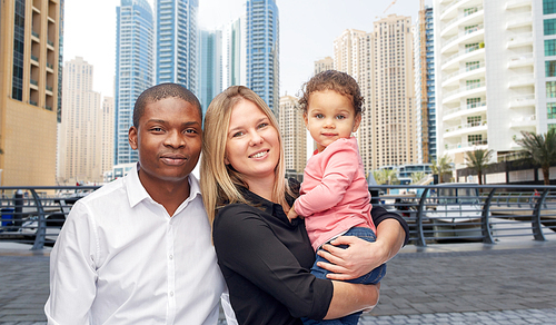 family, travel, tourism and international concept - happy multiracial mother, father and little child over dubai city street background