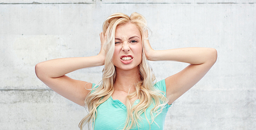 emotions, expressions, stress and people concept - young woman holding to her head and screaming over gray concrete wall background