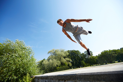 fitness, sport, parkour and people concept - young man jumping in summer park