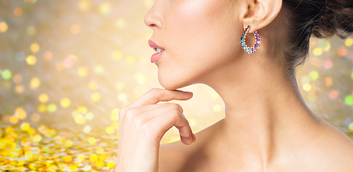 glamour, beauty, jewelry and luxury concept - close up of beautiful woman face with earring over golden holidays lights background