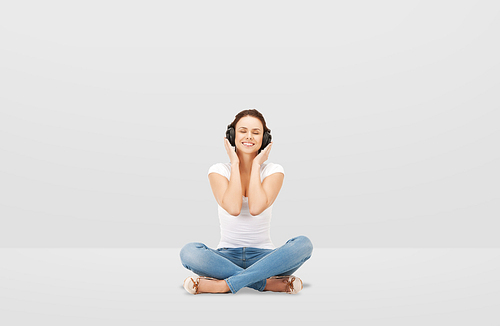 technology, music and happiness concept - smiling young woman or teen girl in headphones over gray background