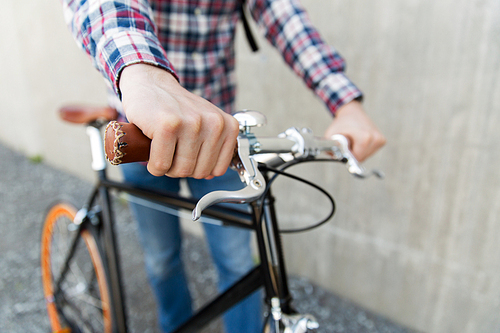 people, travel, tourism, leisure and lifestyle - close up of young hipster man hands holding fixed gear bike wheel on city street