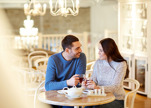 people, communication and dating concept - happy couple drinking tea at cafe or restaurant