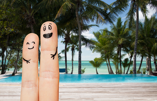 family, travel, summer holidays, tourism and body parts concept - close up of two fingers with smiley faces over exotic tropical beach with palm trees and pool background