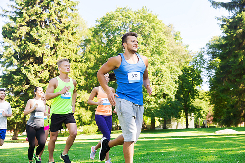 fitness, sport, friendship, race and healthy lifestyle concept - group of happy teenage friends or sportsmen running marathon with badge numbers outdoors