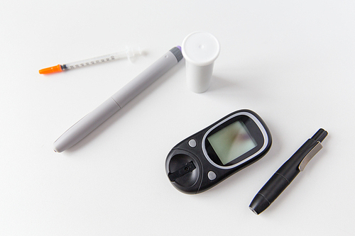 medicine, diabetes, medical tool and health care concept - close up of glucometer, insulin pen and syringe on table