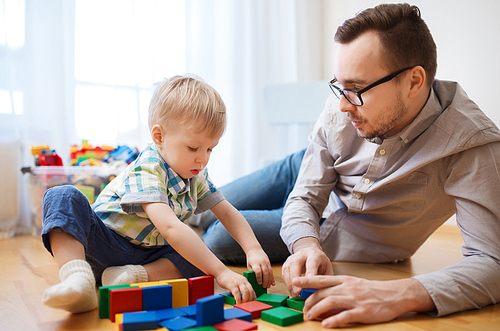 family, childhood, creativity, activity and people concept - happy father and little son playing with toy blocks at home