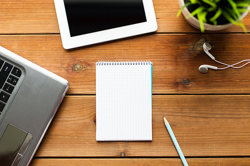 education, business and technology concept - close up of notebook with on laptop computer and tablet pc on wooden table