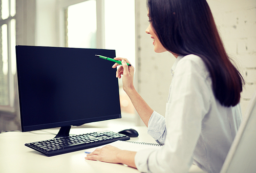 business, people, technology and education concept - close up of woman pointing pen to computer monitor in office