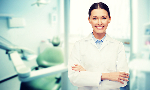 people, medicine, stomatology and healthcare concept - happy young female dentist with tools over medical office background