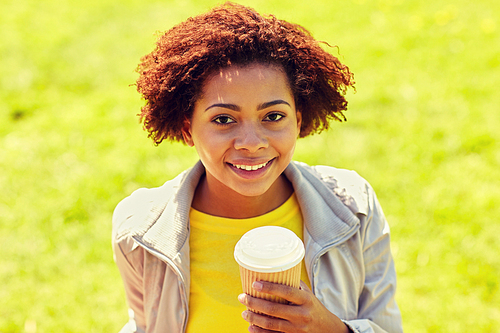 drinks and people concept - smiling african american young woman or teenage girl drinking coffee from paper cup outdoors