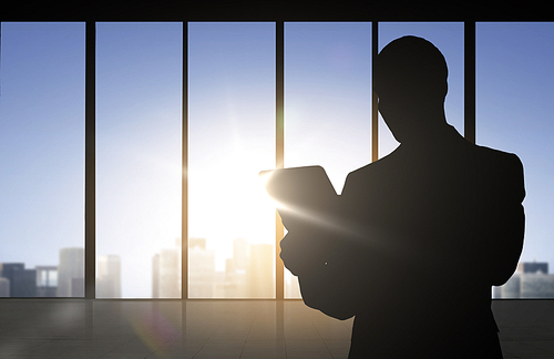 business and people concept - silhouette of business man with tablet pc over office window background