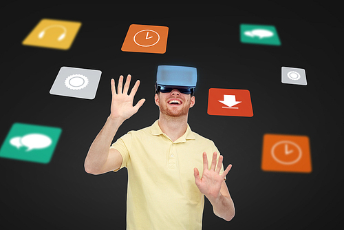 3d technology, virtual reality, entertainment, media and people concept - happy young man in virtual reality headset or 3d glasses playing game over black background with screens and computer icons