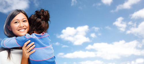 family, children and people concept - happy hugging mother and daughter over blue sky and clouds background