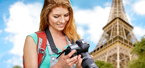 travel, tourism and people concept - happy young woman with backpack and camera photographing over eiffel tower background