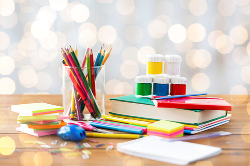 education, school supplies, art, creativity and object concept - close up of stationery on wooden table over holidays lights background