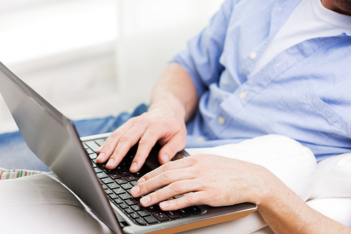 technology, people and lifestyle concept - close up of male hands typing on laptop computer keyboard at home