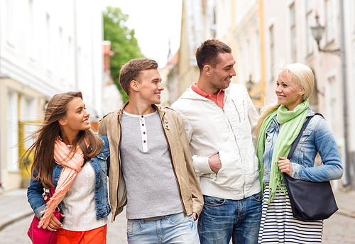 friendship, travel and vacation concept - group of smiling friends walking in the city