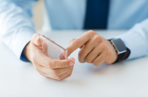 business, technology and people concept - close up of male hand holding and showing transparent smart phone and watch at office