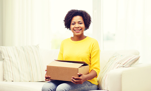 people, delivery, shipping and postal service concept - happy african american young woman holding open cardboard box or parcel at home