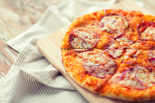 fast food, italian kitchen and eating concept - close up of homemade pizza on wooden table