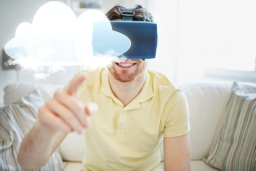 technology, cloud computing, gaming, entertainment and people concept - happy young man in virtual reality headset or 3d glasses with cloud projection at home
