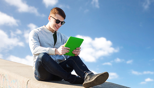 technology, lifestyle and people concept - smiling young man or teenage boy with tablet pc computers over blue sky and clouds background