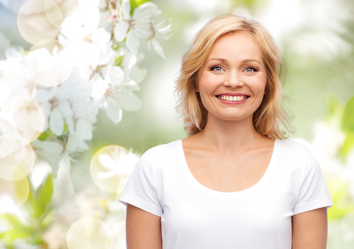 happiness and people concept - smiling woman in blank white t-shirt over natural spring cherry blossom background