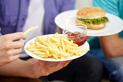 fast food, unhealthy eating, people and junk-food - close up of male hands with french fries, ketchup and hamburger on plates