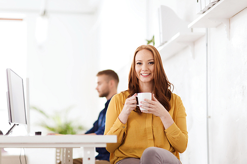 business, startup, people and break concept - happy businesswoman drinking coffee or tea at office