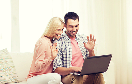 family, technology, internet communication and happiness concept - smiling happy couple with laptop waving hands computer at home