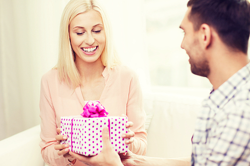 relationships, love, people, birthday and holidays concept - happy man giving woman gift box at home