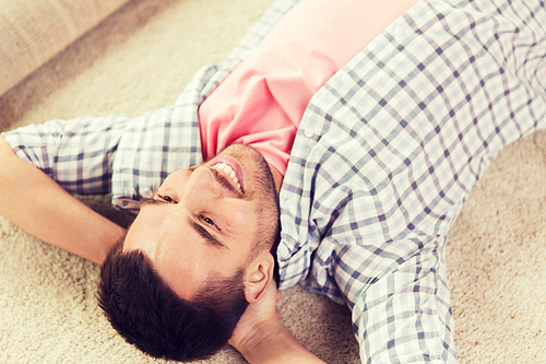 people, repair and renovation concept - happy man lying carpet or rug on floor at home