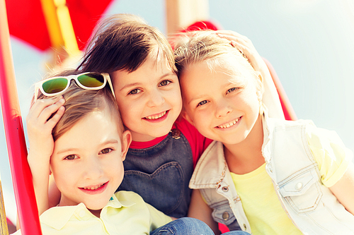 summer, childhood, leisure, friendship and people concept - group of happy kids hugging on children playground