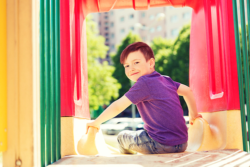 summer, childhood, leisure and people concept - happy little boy on slide at children playground