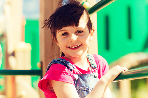 summer, childhood, leisure and people concept - happy little girl on children playground climbing frame