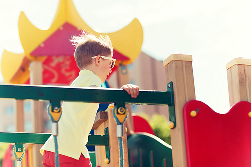 summer, childhood, leisure and people concept - happy little boy on children playground climbing frame