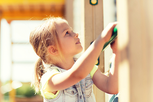 summer, childhood, leisure and people concept - happy little girl on children playground climbing frame