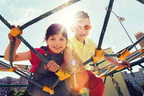 summer, childhood, leisure, friendship and people concept - group of happy kids on children playground climbing frame