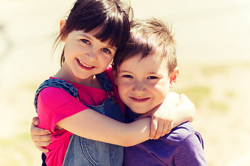 summer, childhood, family, friendship and people concept - two happy kids hugging outdoors