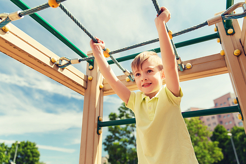 summer, childhood, leisure and people concept - happy little boy on children playground climbing frame