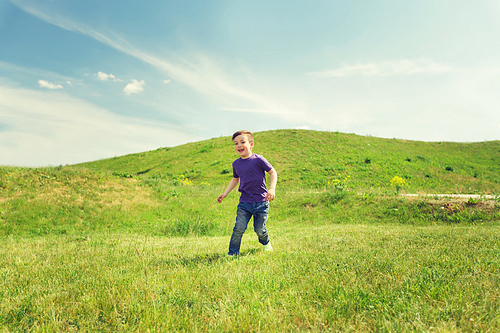 summer, childhood, leisure and people concept - happy little boy running on green field outdoors